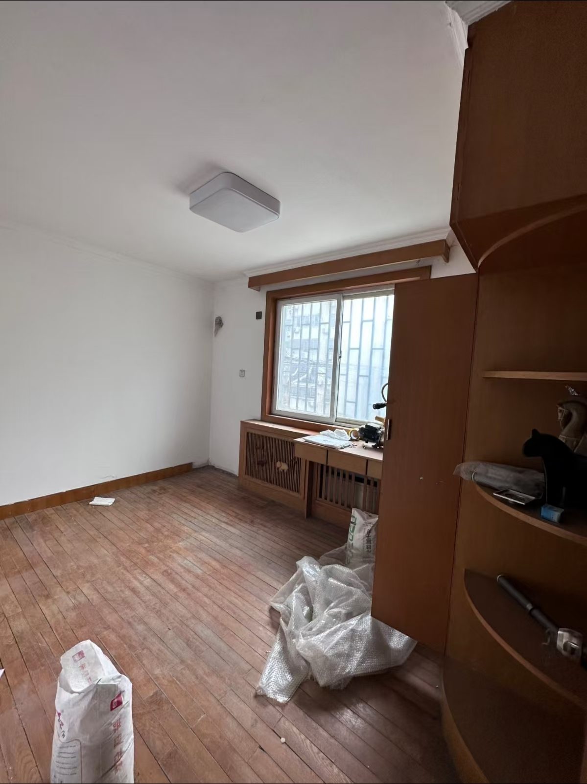 房改办家属院改造前的次卧,旧地板与零散柜体